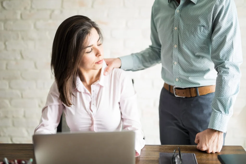 An employer standing over a female employee with his hand on her shoulder. If you're experiencing sexual harassment at work our San Antonio sexual harassment lawyers will support you in your pursuit of a lawsuit.