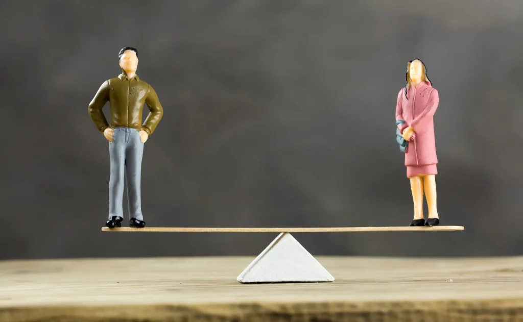 A man and a woman standing in perfect balance on a board, showing that neither of them are experiencing discrimination or harassment regarding their gender. If you're experiencing discrimination, contact a discrimination lawyer in San Antonio.