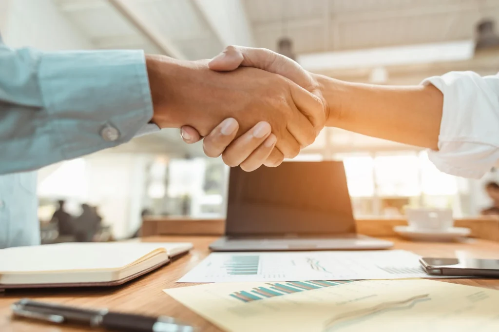 An employer and employee shaking hands after discussing an employment agreement. We recommend consulting an employment contract lawyer in San Antonio before signing agreement documents.