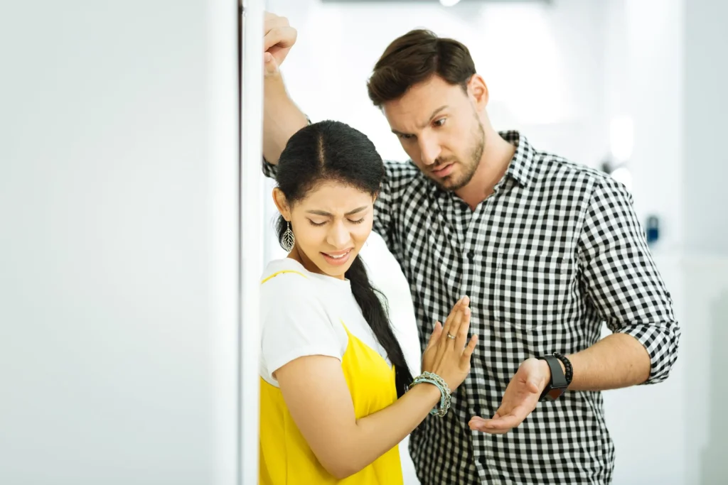 A woman up against the wall cringing as a male towers over her. If you're experiencing unending sexual harassment at work, we suggest contacting a Brownsville sexual harassment lawyer immediately.