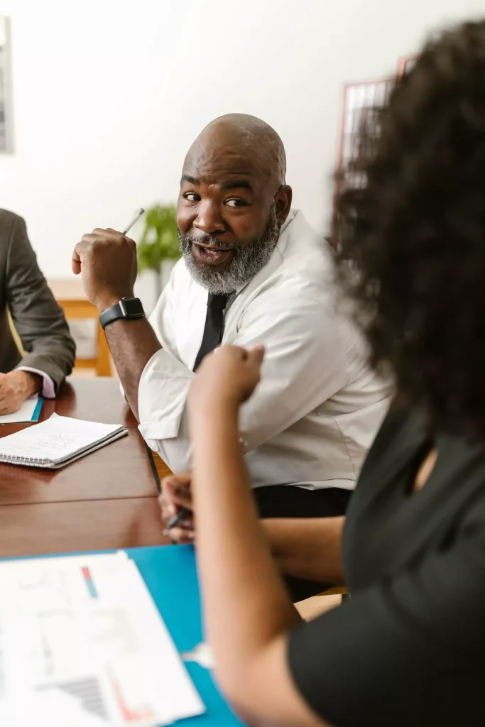 An older man speaking with a woman at work.