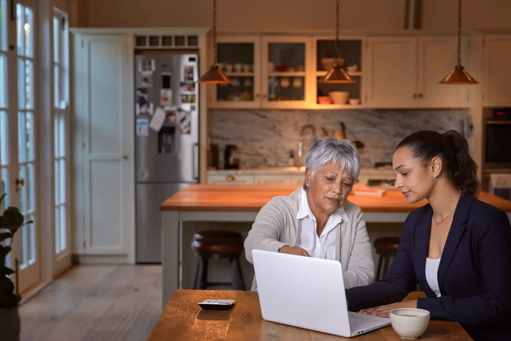 An older woman speaking with her attorney and looking at a laptop.