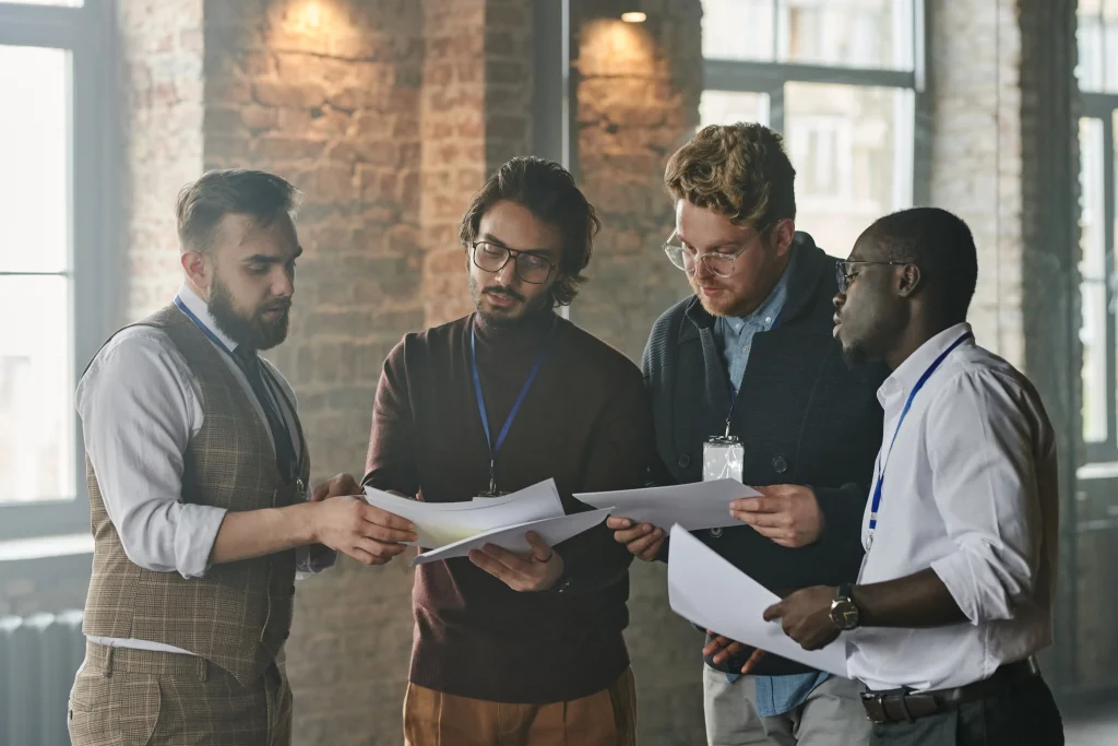 A group of employees standing and discussing paperwork together.