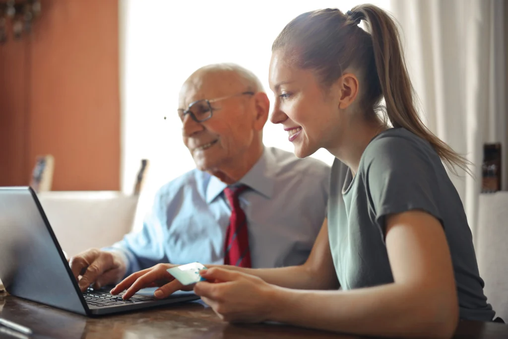 Two coworkers of different ages collaborating and working together on a laptop.