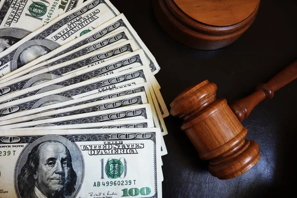 A pile of hundred dollar bills lies next to a gavel.