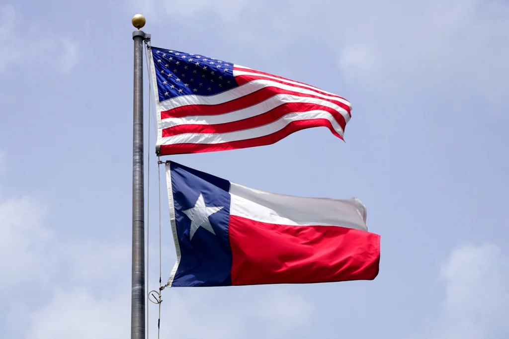 A United States and Texas State flag hanging and blowing in the wind.