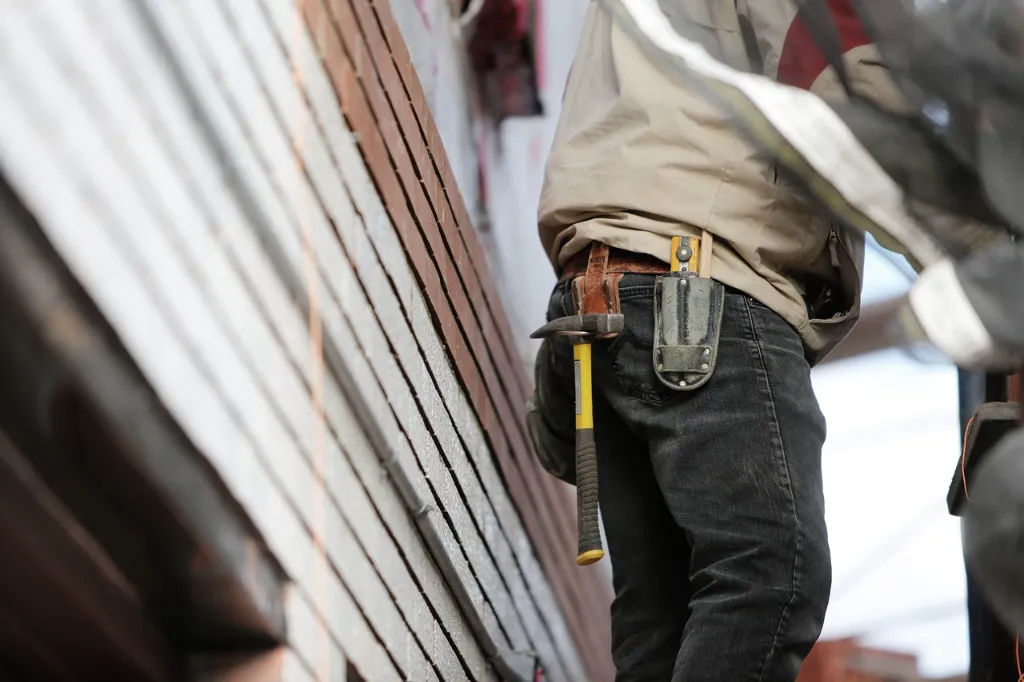 A construction worker with a tool belt on a roof.