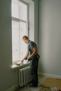 A construction worker painting a window sill.