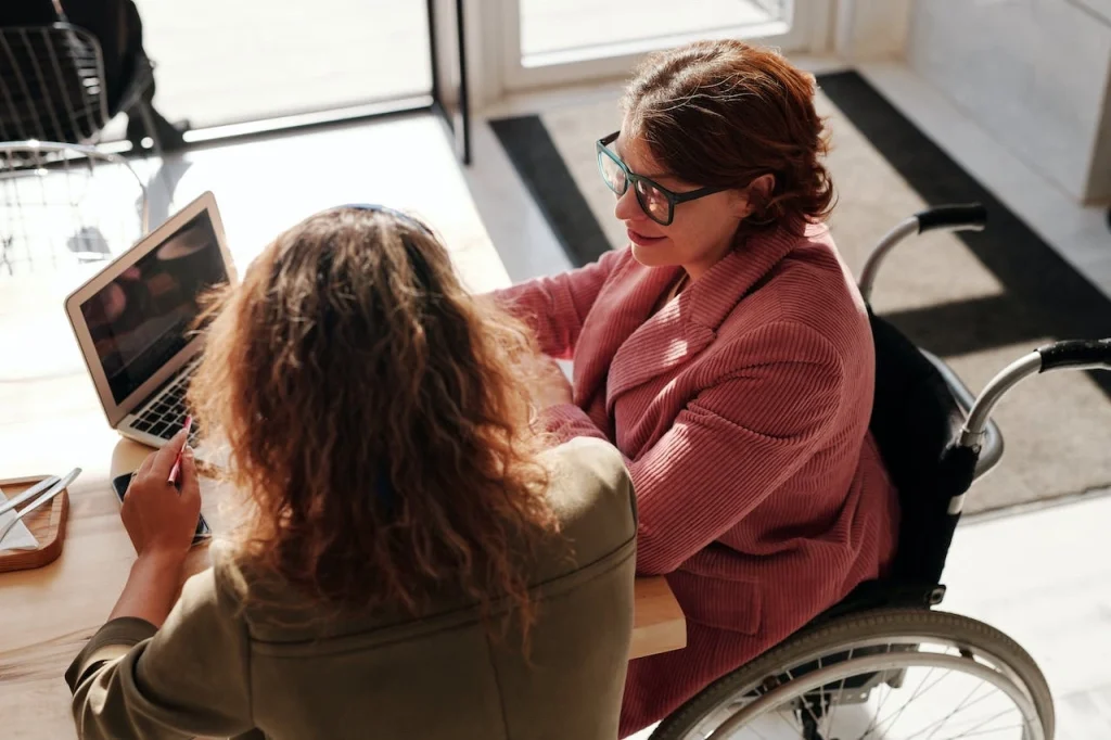 A woman in a wheelchair at her desk working with a coworker.