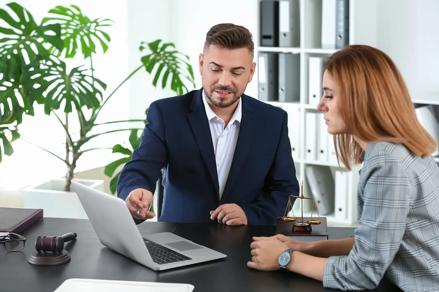 An attorney showing his client something on a laptop.