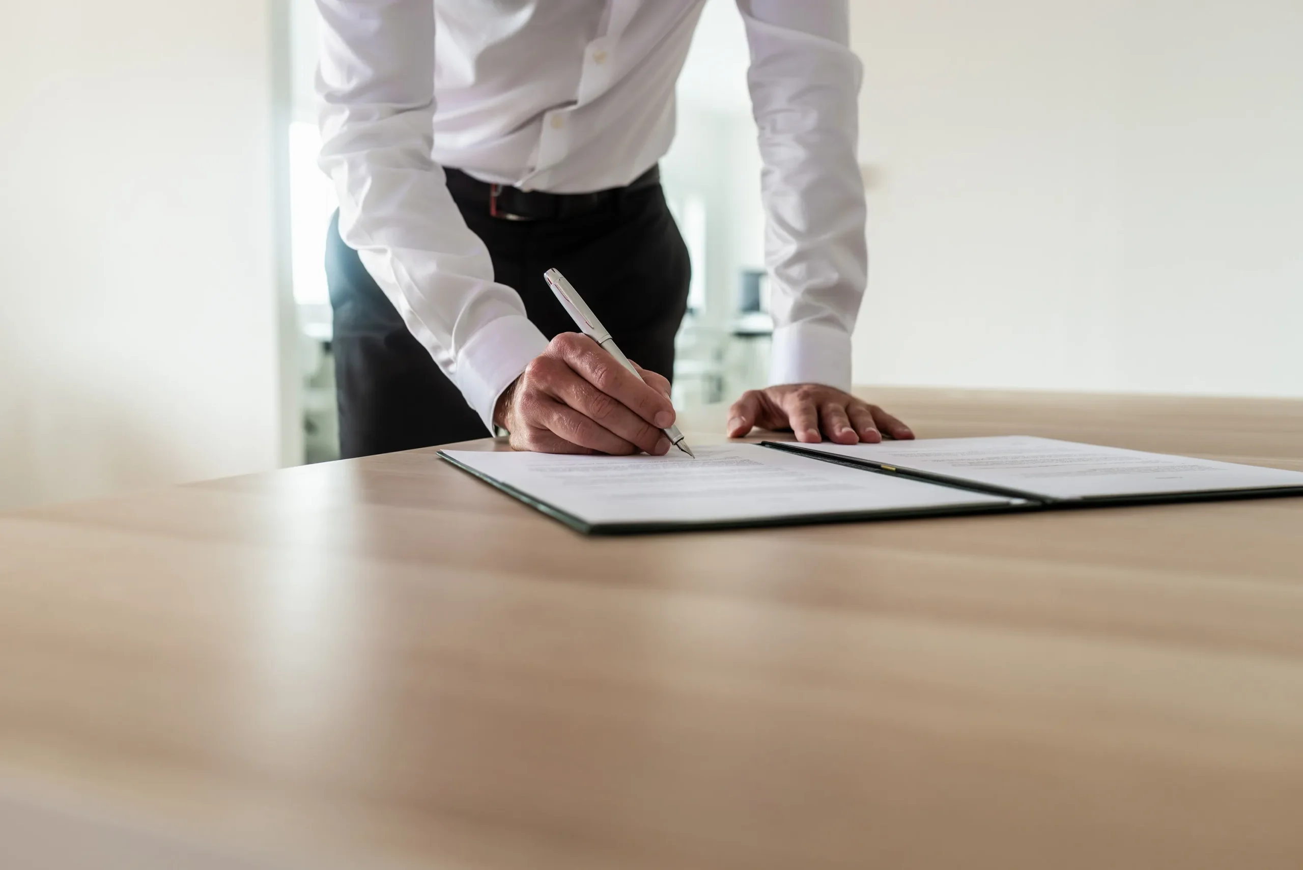 A business man signing paperwork while standing.