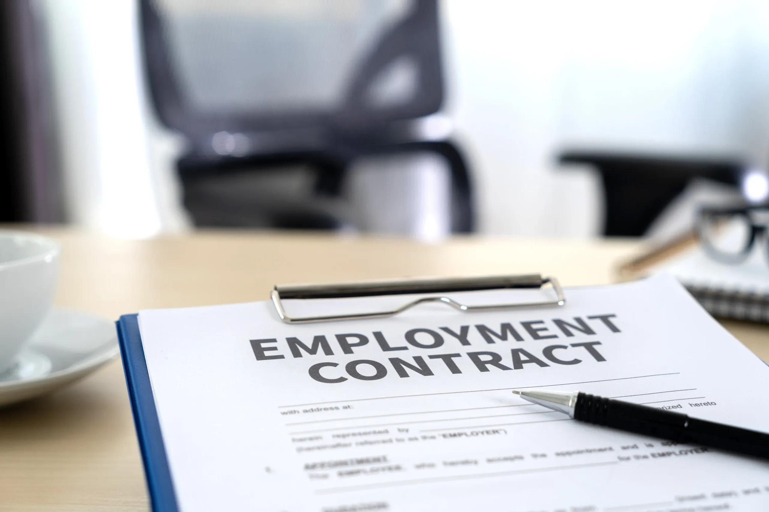 An employment contract form on a clipboard.
